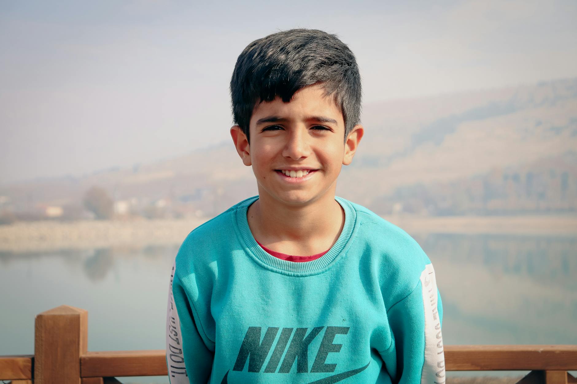 Portrait of a smiling young boy wearing a blue sweater by the river in Malatya, Türkiye.