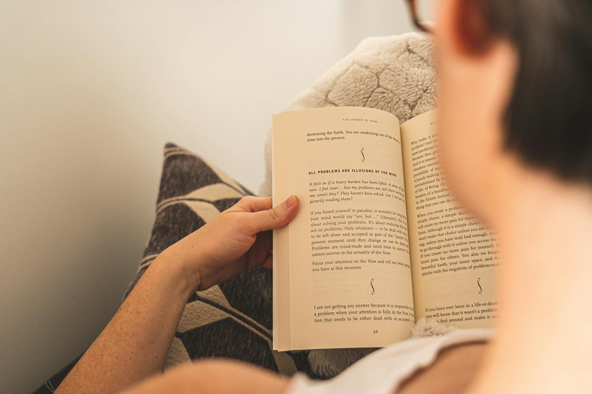 Woman enjoying relaxation by reading a book on a cozy couch indoors.