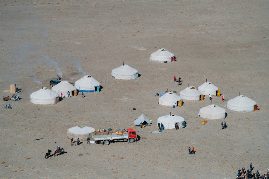 Aerial view of traditional yurts and people in a remote desert setting.