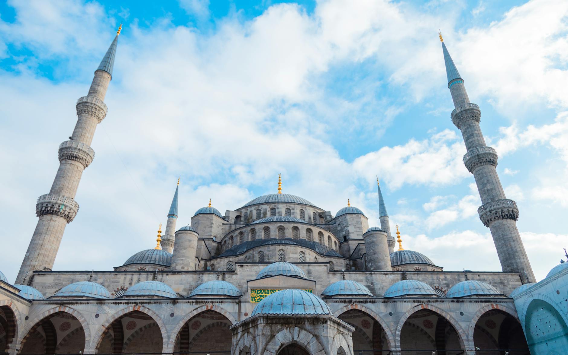 Beautiful low angle shot of the iconic Blue Mosque in Istanbul with minarets and a clear blue sky, showcasing classic Ottoman architecture.