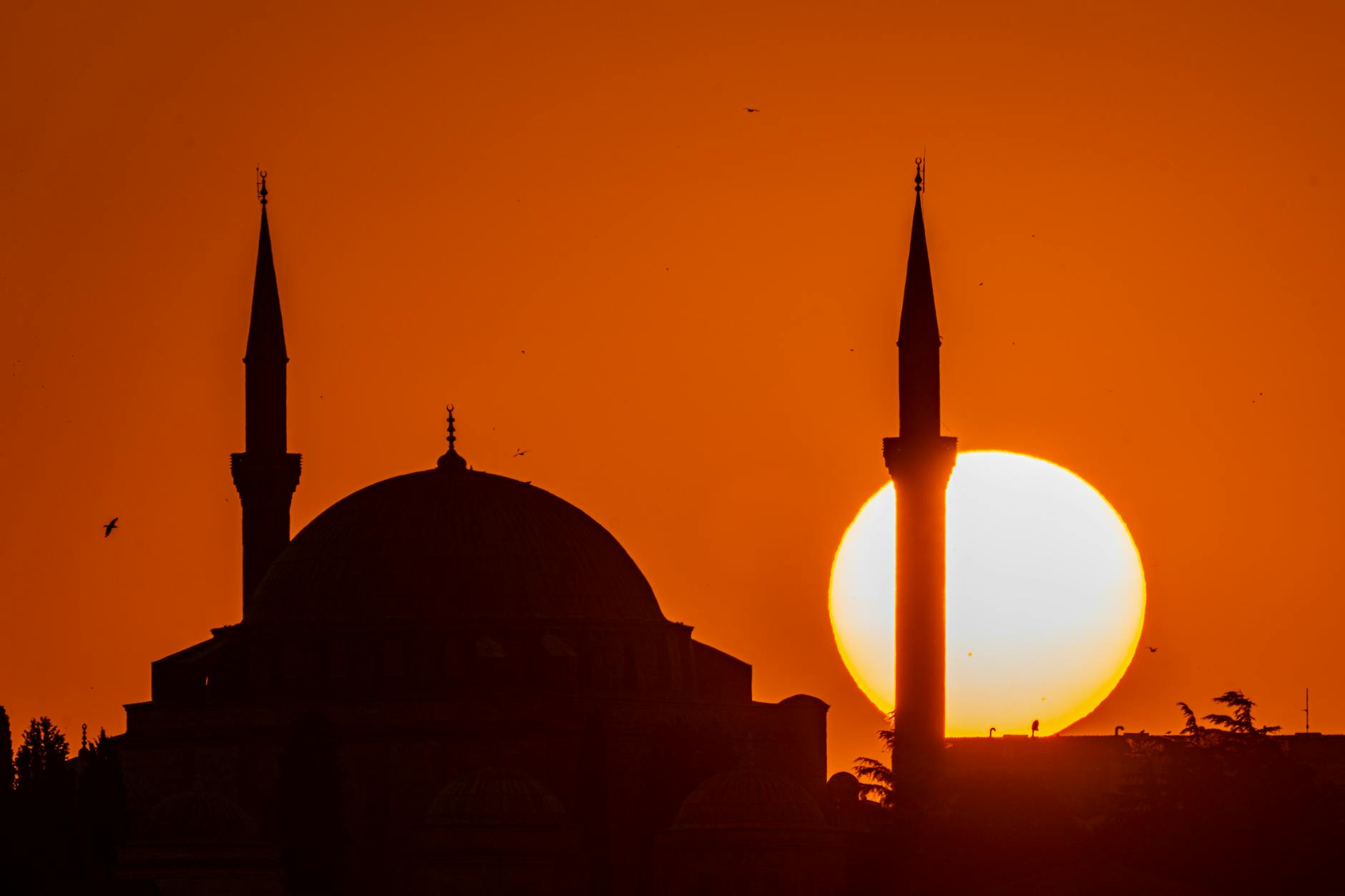 Silhouette of Yavuz Sultan Selim Mosque in Ankara, Türkiye, with a dramatic orange sunset.