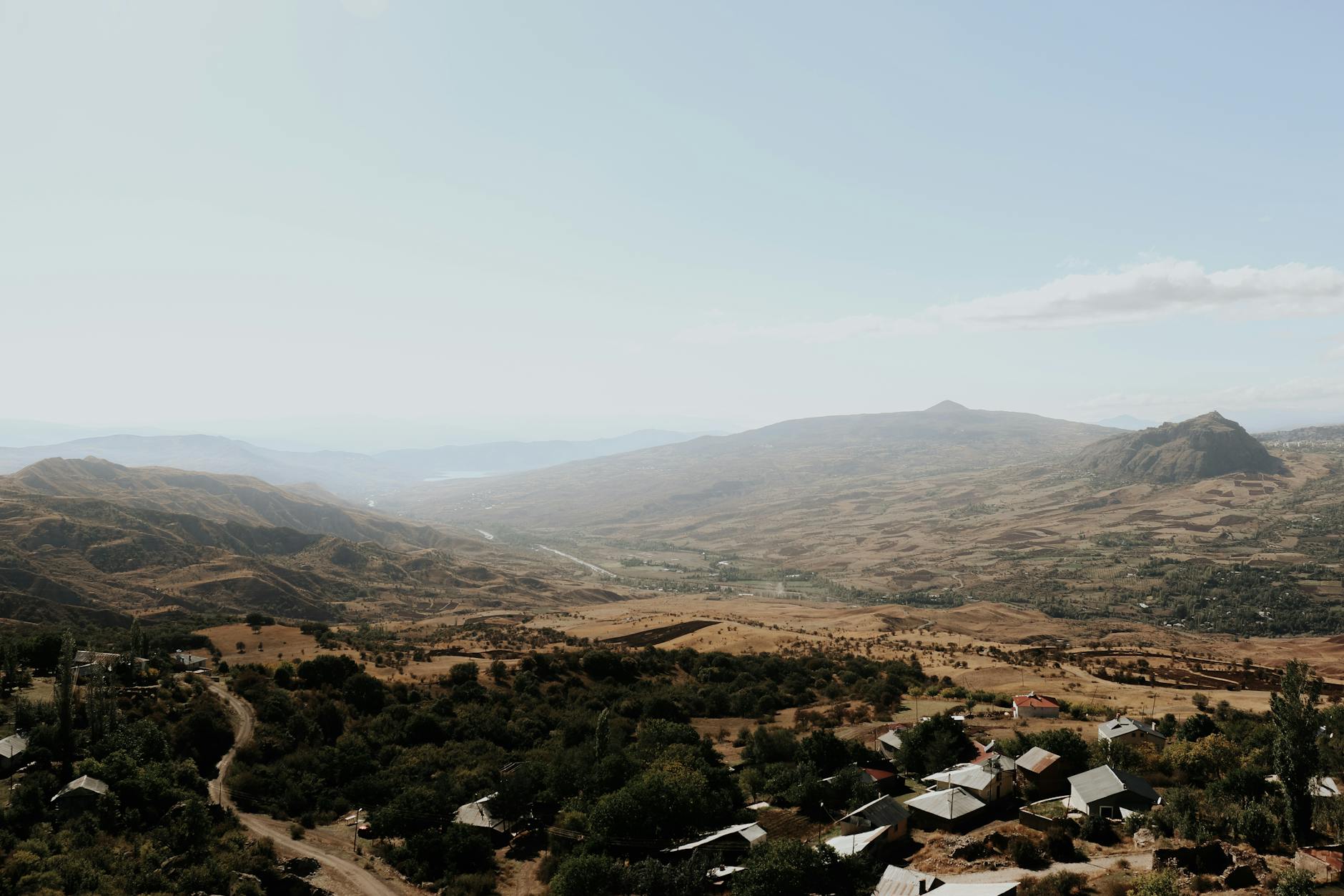 A breathtaking aerial view of a serene rural landscape with distant mountains and scattered houses.