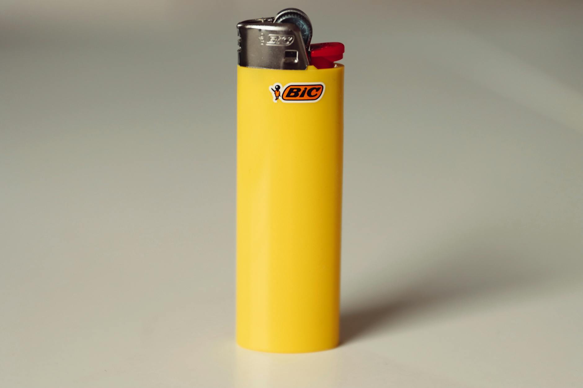 Close-up of a yellow Bic lighter on a white background for studio product showcase.