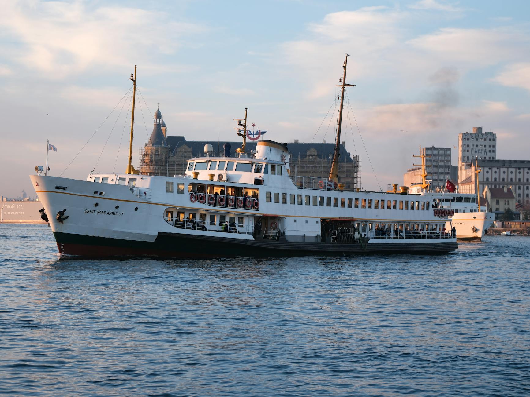 A traditional ferry sails the Bosphorus in Istanbul with Kadikoy Terminal in the backdrop.
