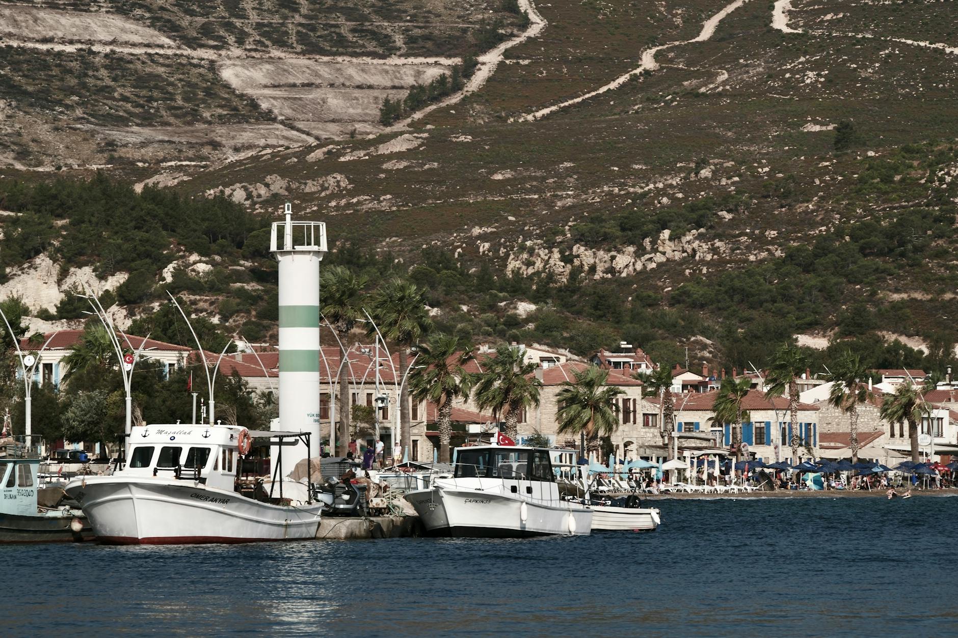 View of colorful fishing boats docked at Foça harbor with a scenic backdrop.