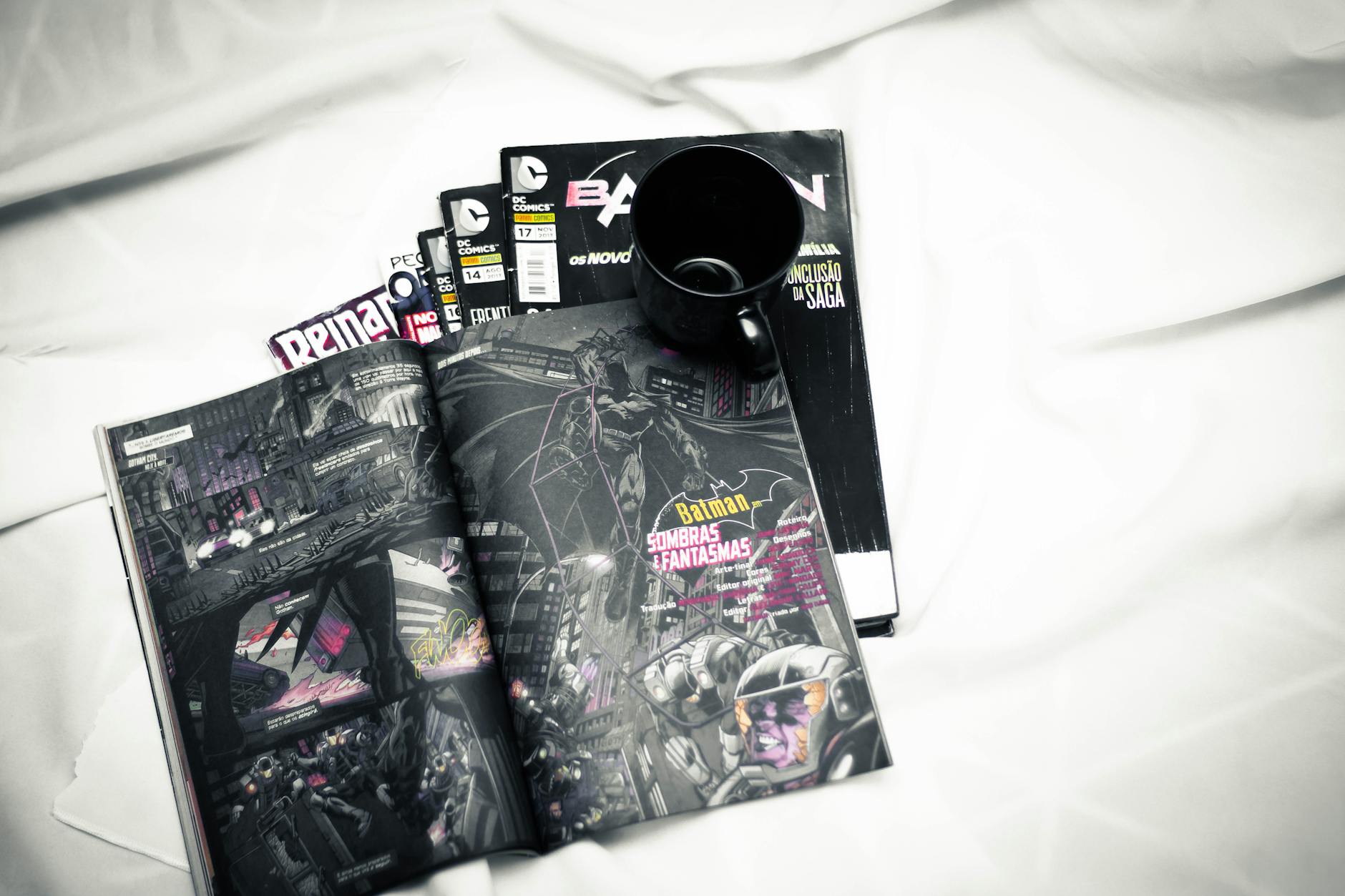 Open comic book and mug resting on a bed for a cozy reading vibe.